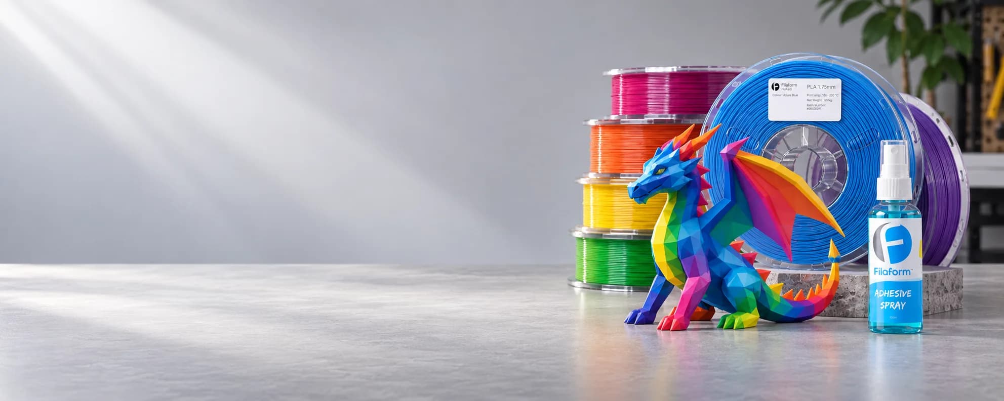 Filaform filament spools, a printed rainbow dragon and the Adhesive Spray on a studio bench