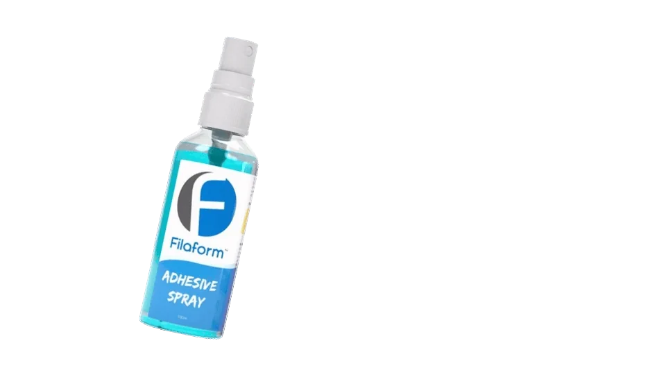 A bottle of Filaform Adhesive Spray misting a light, even coat